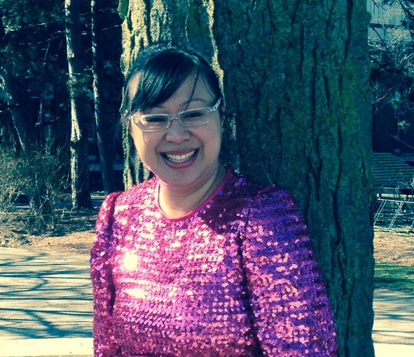 Head and shoulder shot of Kim Nguyen standing in front of a tree in a purple sequins dress