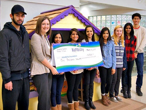 Members of the Believe 4 Kids campus club holding $1000 cheque