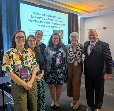 Six presenters in front of presentation screen displaying the title  An International Perspective on Safeguarding in Community Sport.