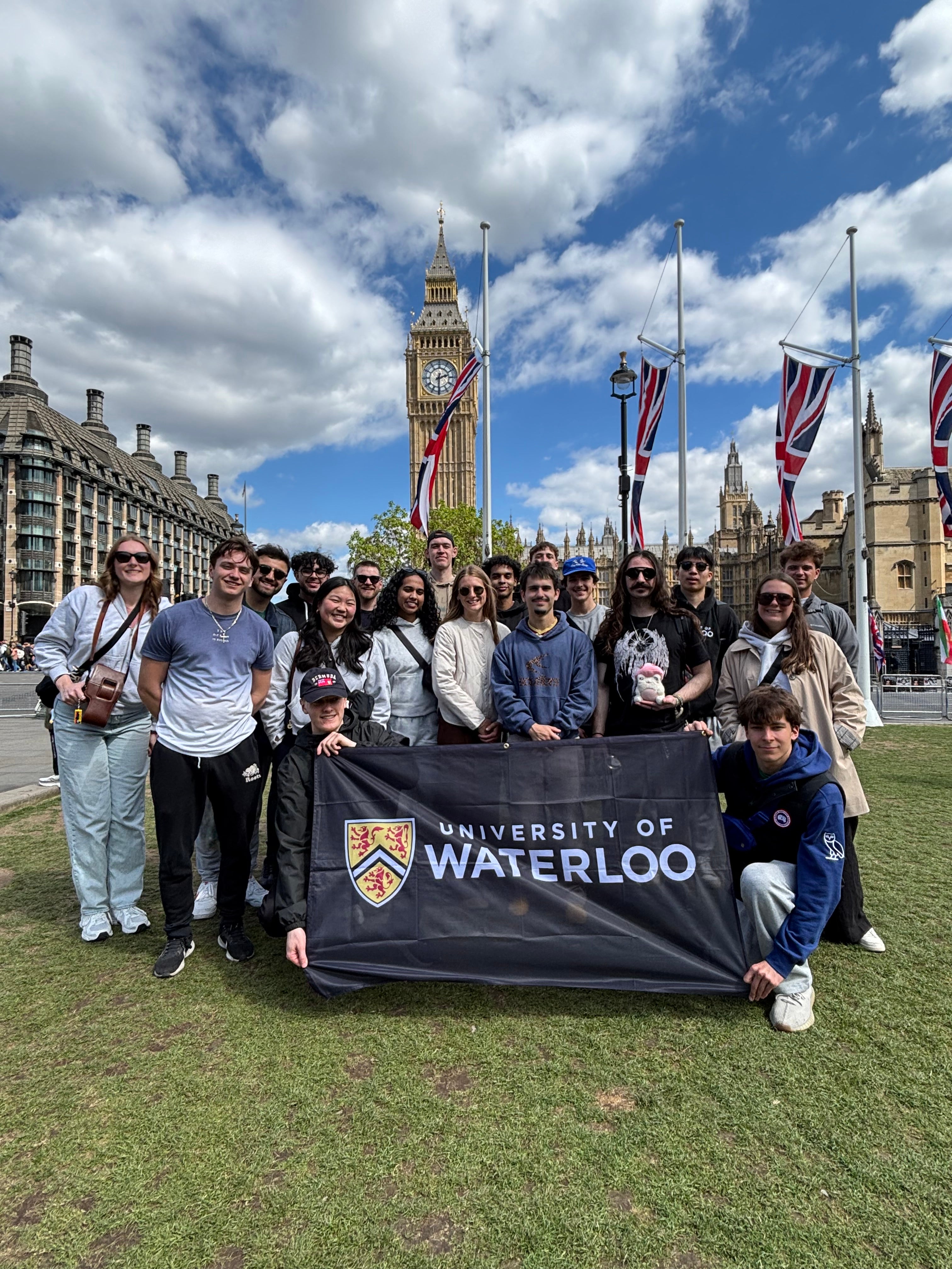 A group of students gathered in front of the Big Ben Tower holding up a University of Waterloo Flag