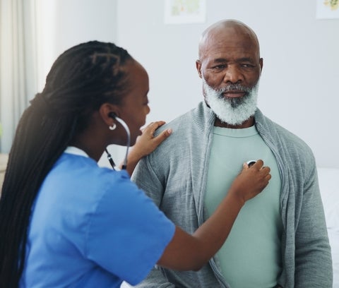 A person holding a stethoscope listens to a patient's heart