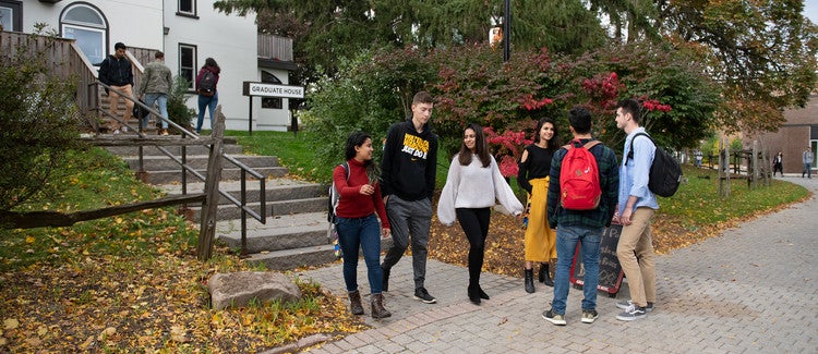 Students standing outside of the grad house building