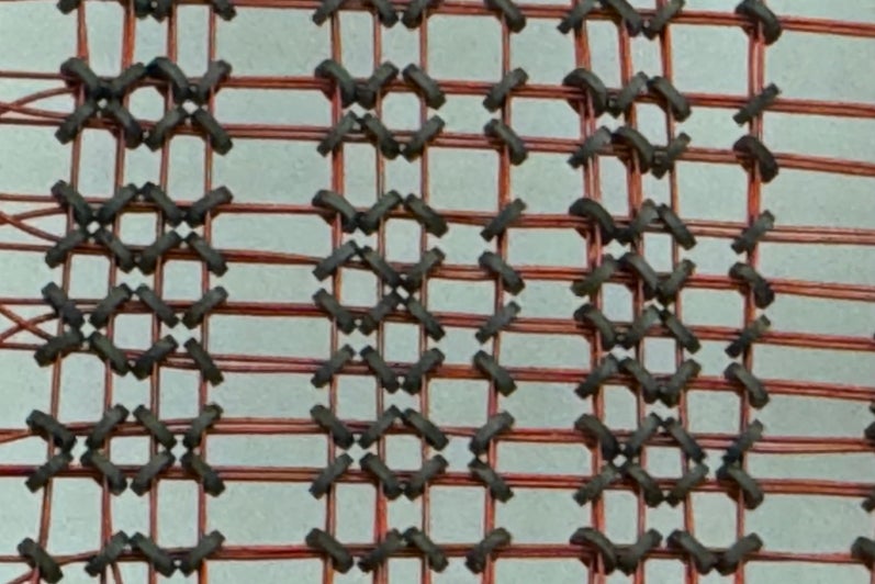 Close image of a core memory board with torroids visible 