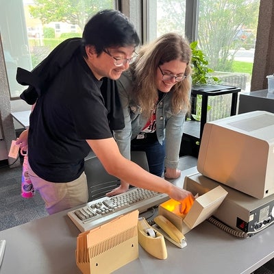 Two people interacting with a retro computer.