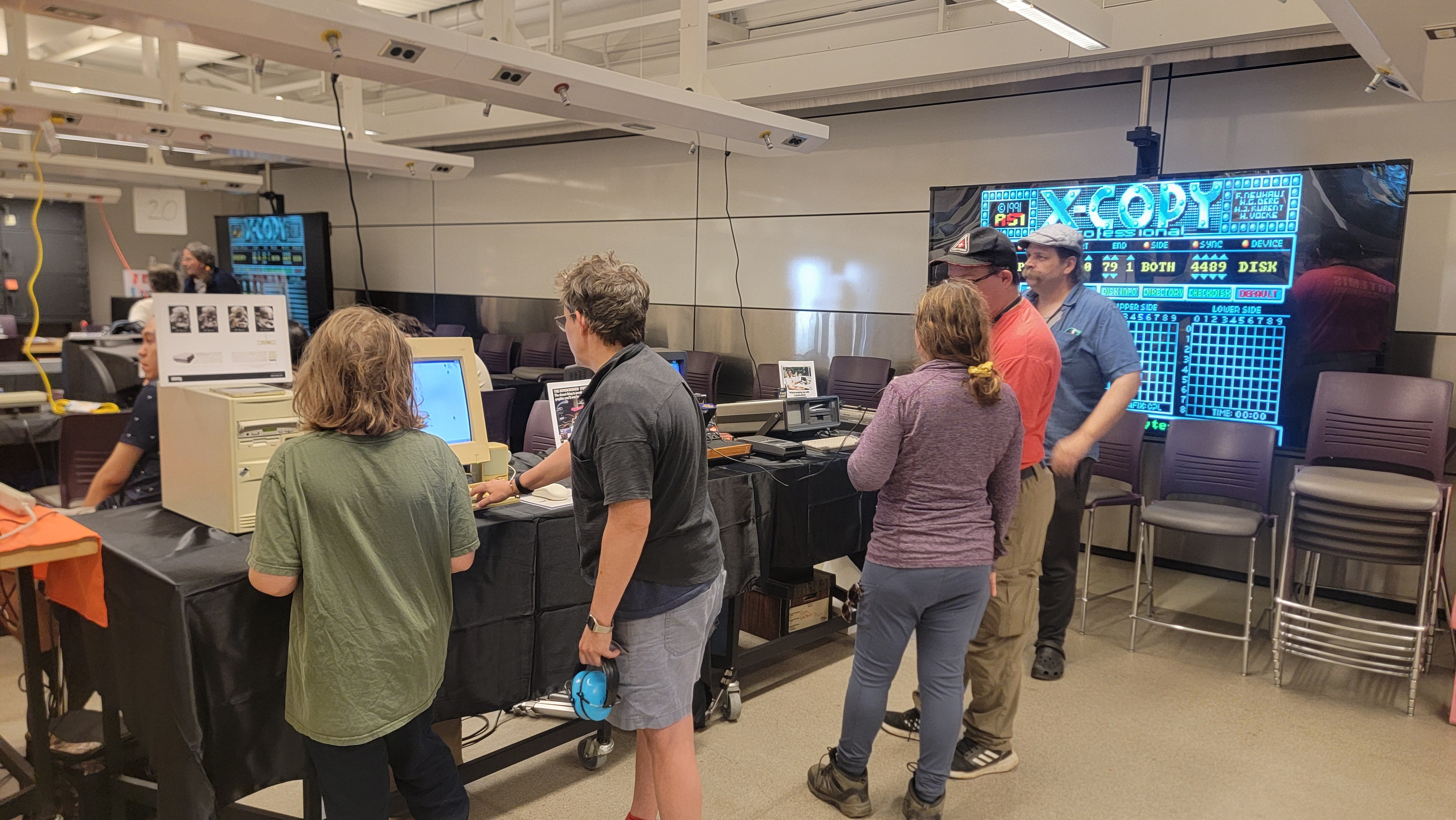 Attendees interacting with an exhibit with a screen in the background displaying the words "X-COPY".