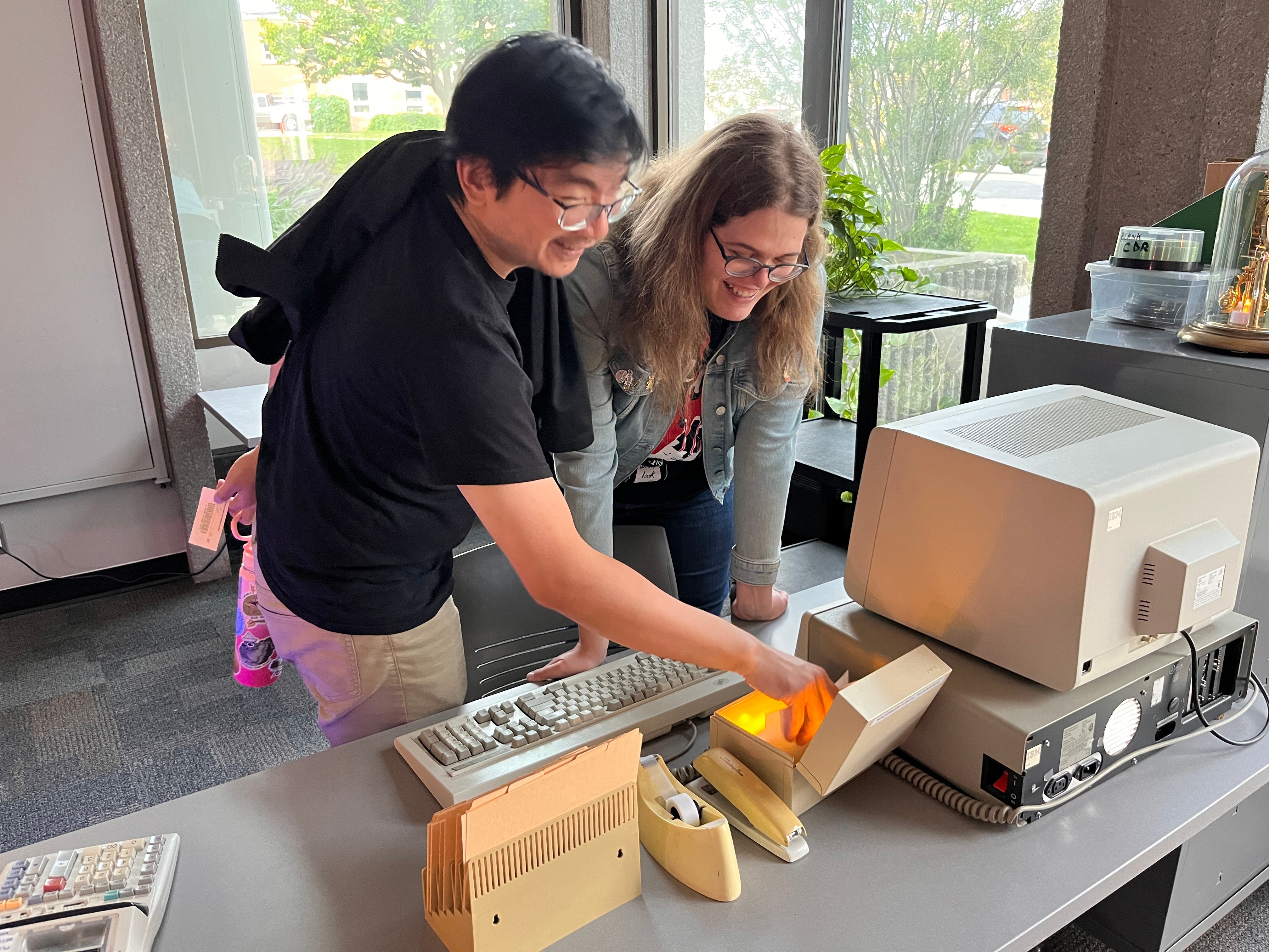 Two people interacting with a retro computer.
