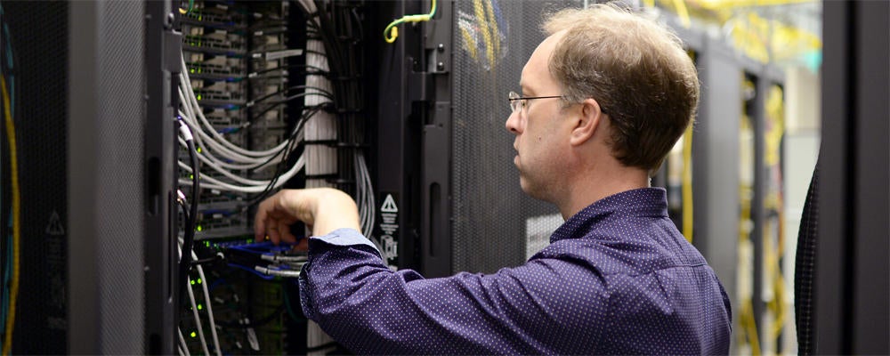 Staff member (Lori) works on data cabling in a server rack.