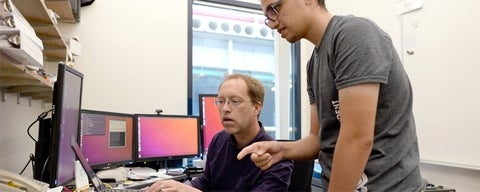 Staff member (Lori) works on a laptop with a grad student.