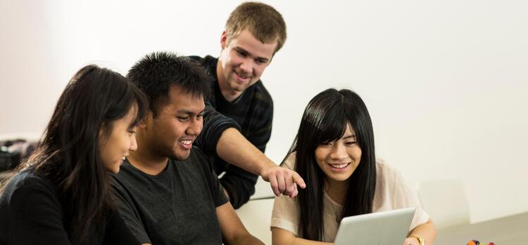 Four students working together on a laptop