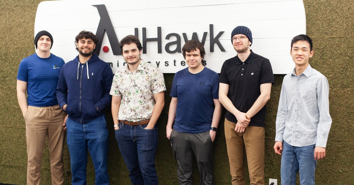 group photo of co-op students posing in front of a wall with AdHawk Microsystems's logo