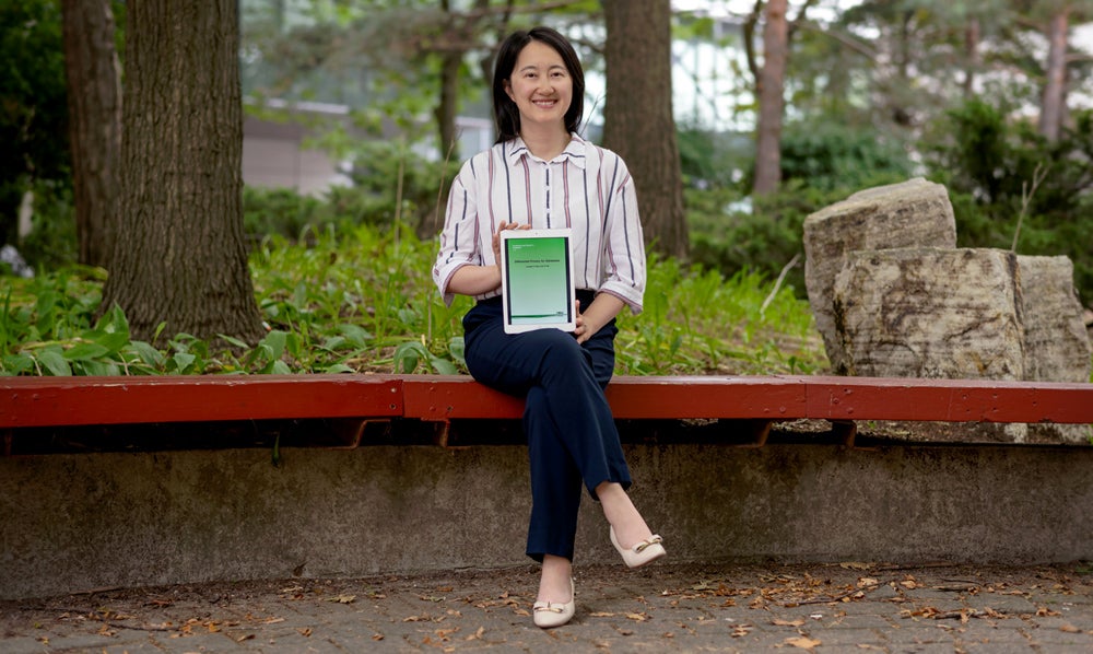 photo of Professor Xi He holding her book, Differential Privacy for Databases