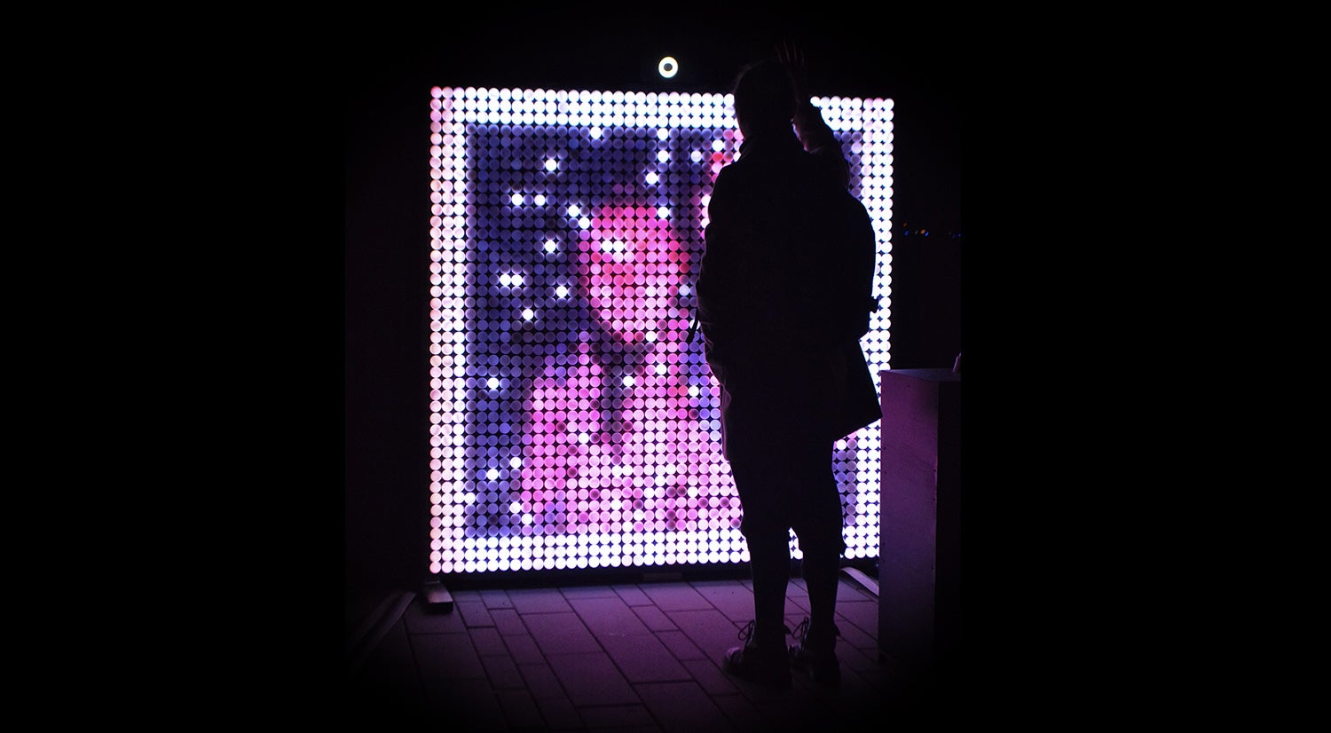 image of a person standing in front of The Light Within exhibit