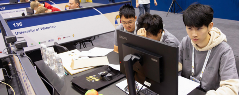 banner photo of three students coding on a computer inside their competition booth