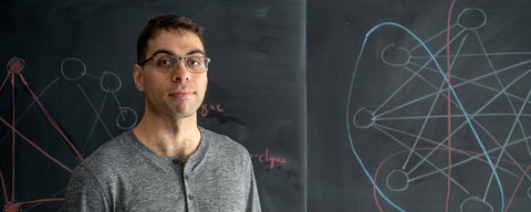 PhD student Cameron Seth in front of a blackboard