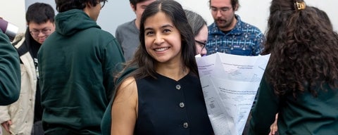 Nikhita donning a navy-blue dress, holding a bouquet (which is composed of her research papers)