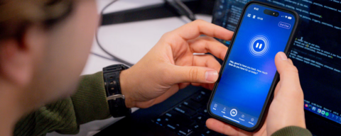 Close-up of someone holding a phone. The screen is blue and it reads "Hey good to have you back. How much time do you have for us today?""