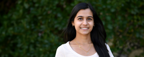 landscape photo of phd student Nikhita Joshi standing in front of a green leafy background