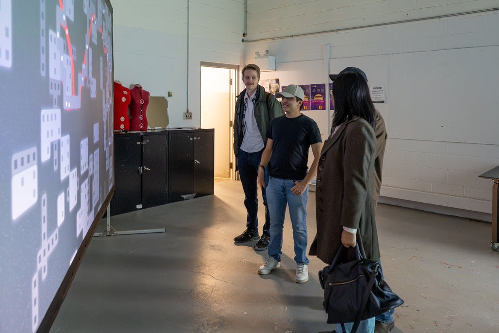Four people standing in front of a screen depicting Desire Paths