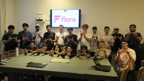 Photo of the Waterloo Blockchain standing in front of a screen and doing the "W" hand sign 