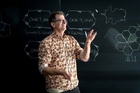 Professor Craig S. Kaplan juggling chalk in front of a blackboard