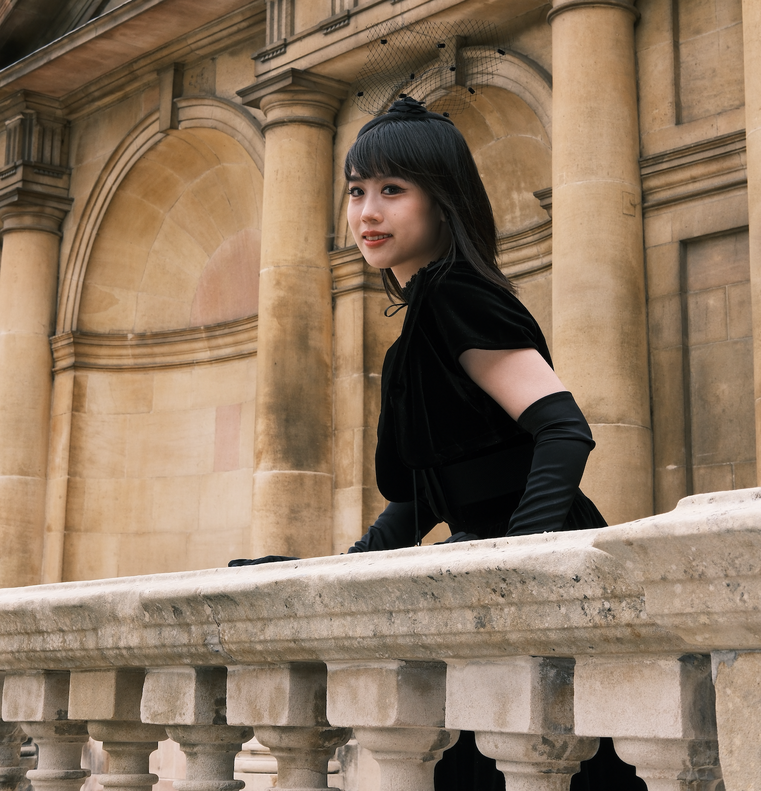 yuzhe you dressed in black holding a railing at a castle-like building
