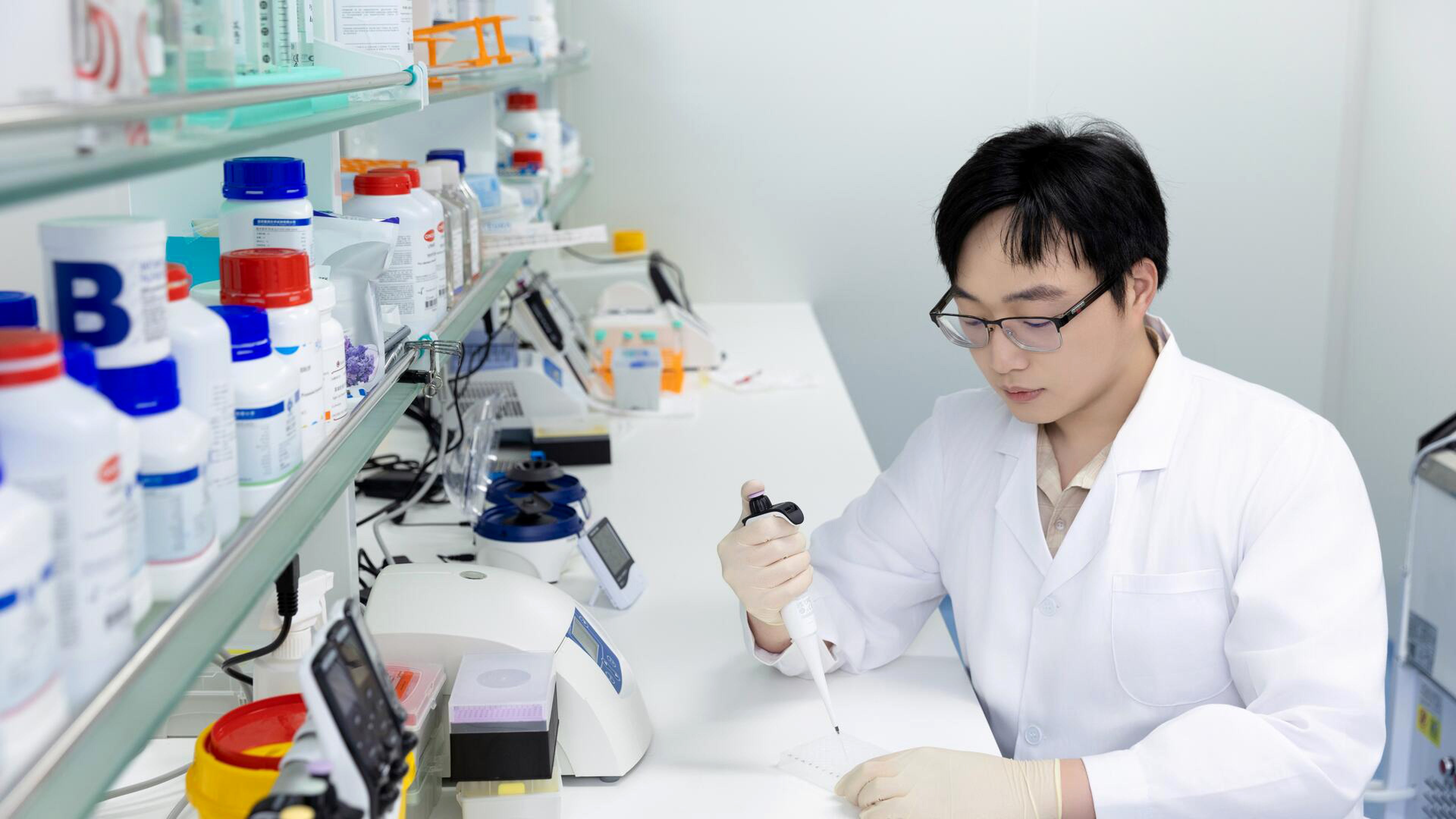 Zeping Mao holds a pipette in a biology wet lab