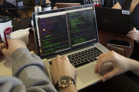 Hands typing on a computer running code