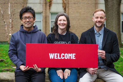 Co-Directors and CFM Program Manager sitting outside holding a welcome sign