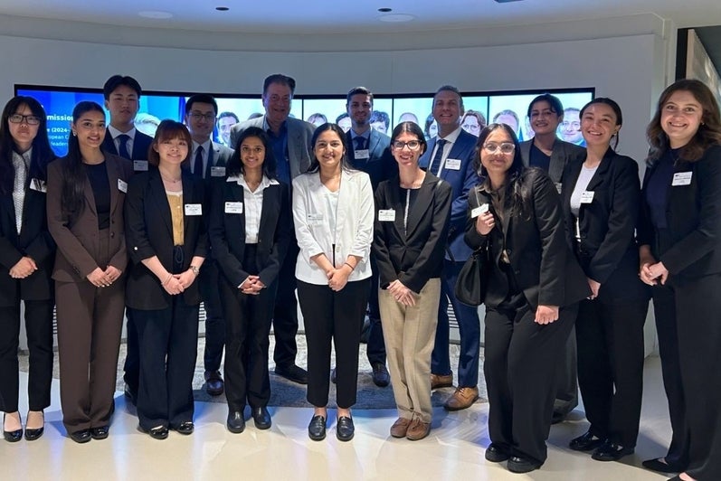 Fourteen people standing for a photo in business suits