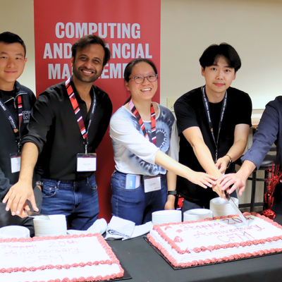 Five alumni cutting cake with a knife
