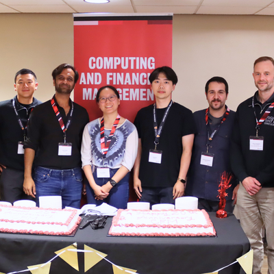 Five alumni, 1 professor and 1 staff standing with two cakes