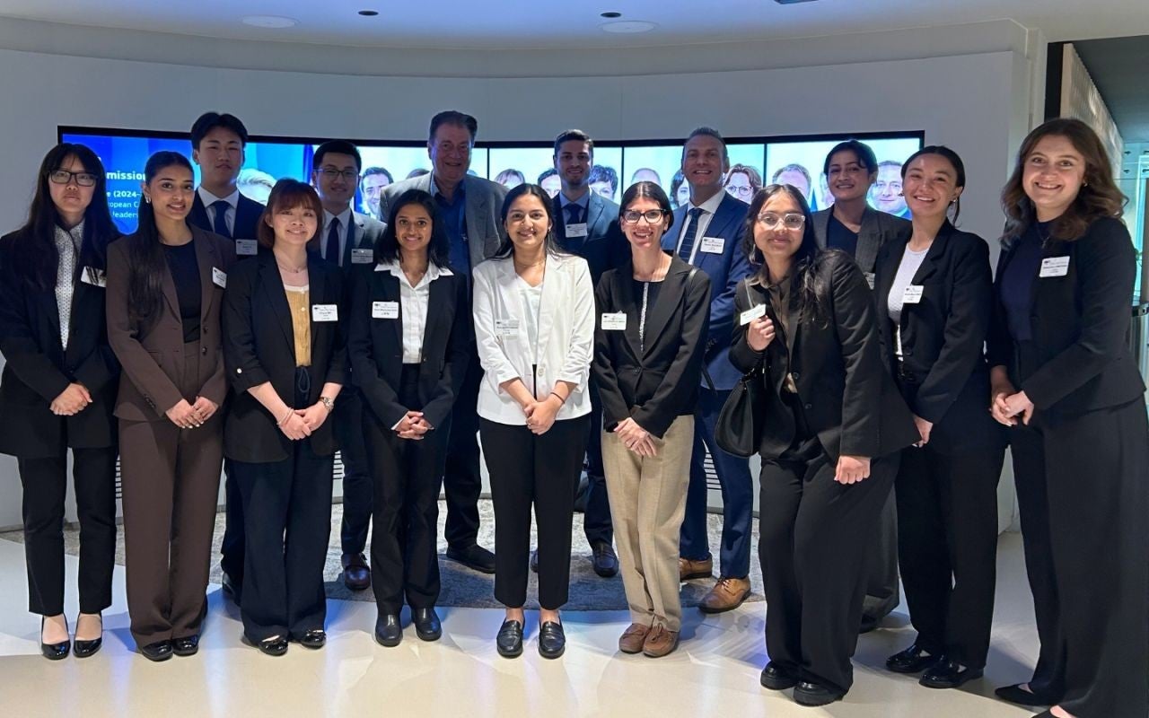 Fourteen people standing for a photo in business suits