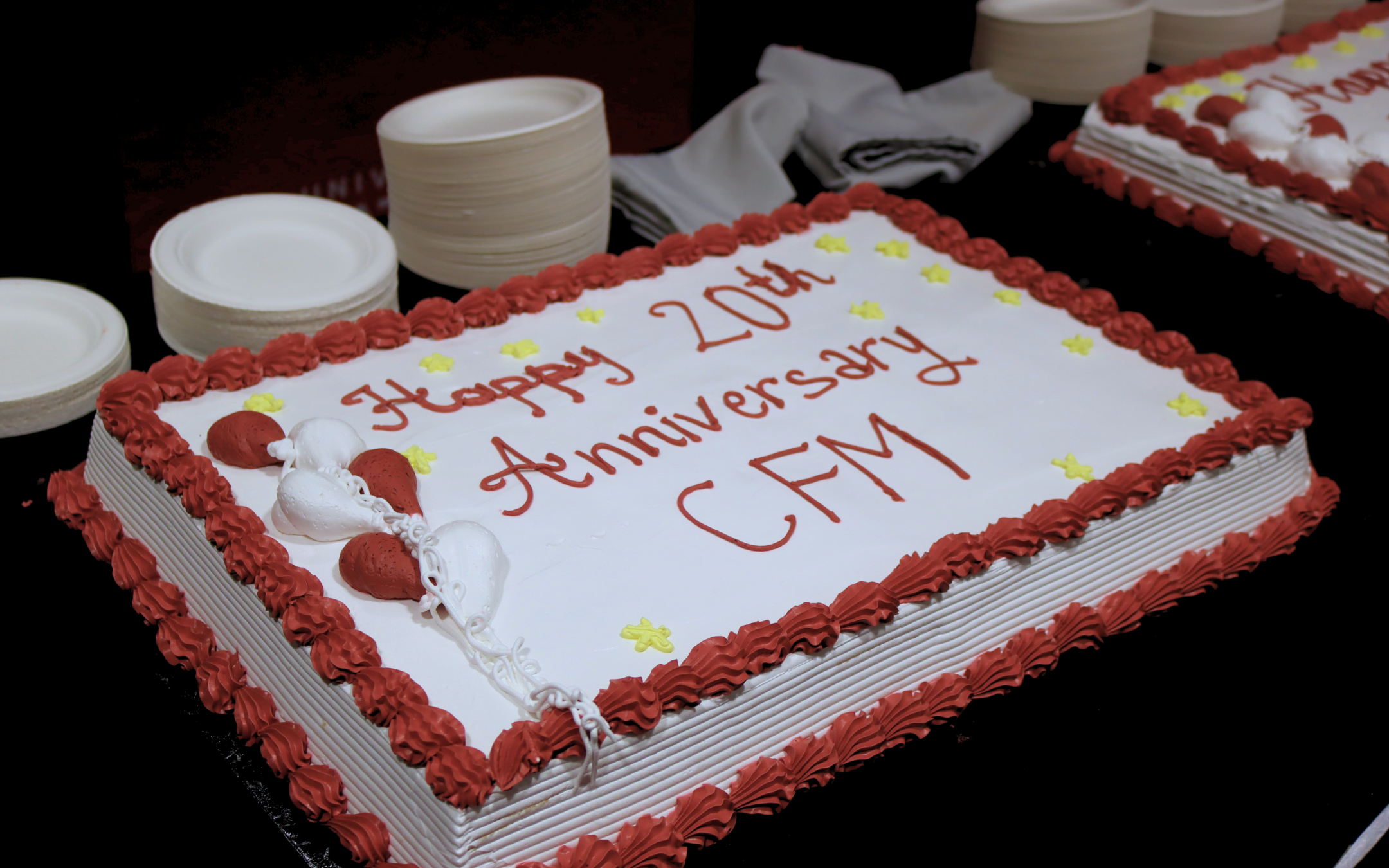 A red and white decorated cake that reads Happy 20th Anniversary, CFM