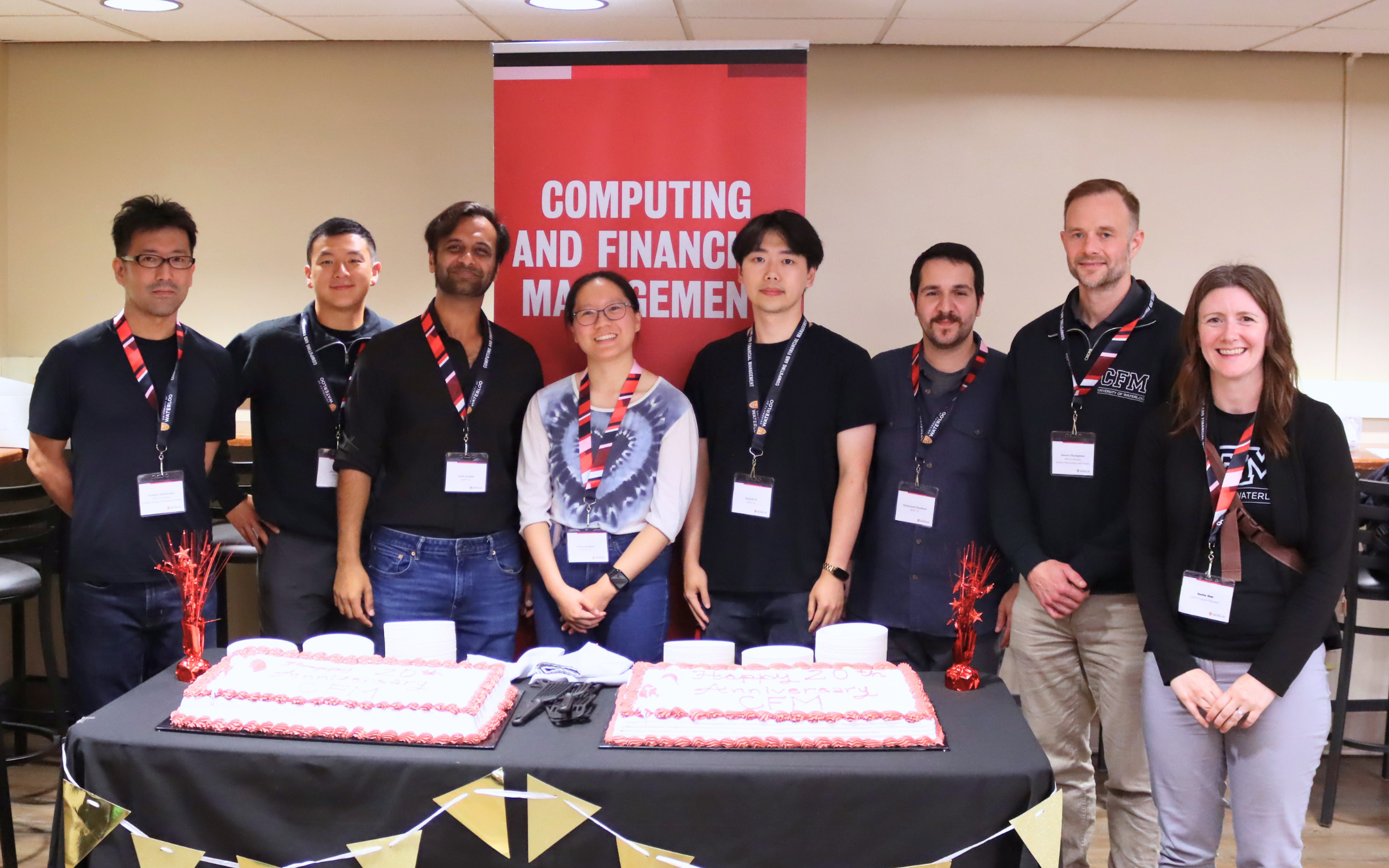 Five alumni, 1 professor and 1 staff standing with two cakes