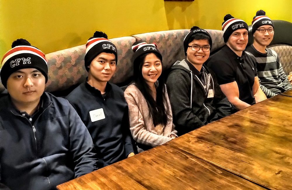 Six alumni wearing CFM hats