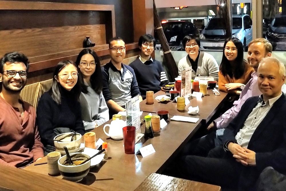 A group of 10 people sitting at a table for sushi dinner