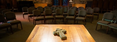 Celtic cross on a table with chairs in the background