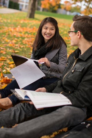two students sitting outside with papers