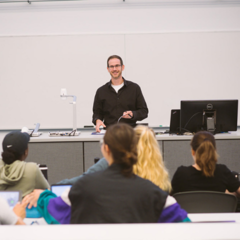 A faculty member teaching in the front of the classroom