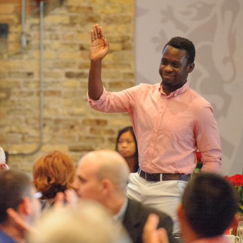 An MBET student smiling and raising their hand in a crowd