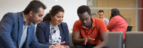 Three MBET students discussing a project in the Conrad Hub space