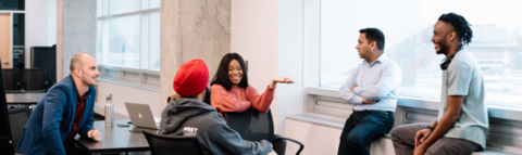 students sit at a table with mentor speaking to them