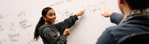 Undergraduate students pointing to whiteboard discussing programs and offerings