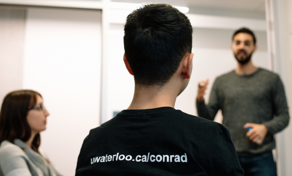 Three students sit in Conrad room, conrad t-shirt undergrad