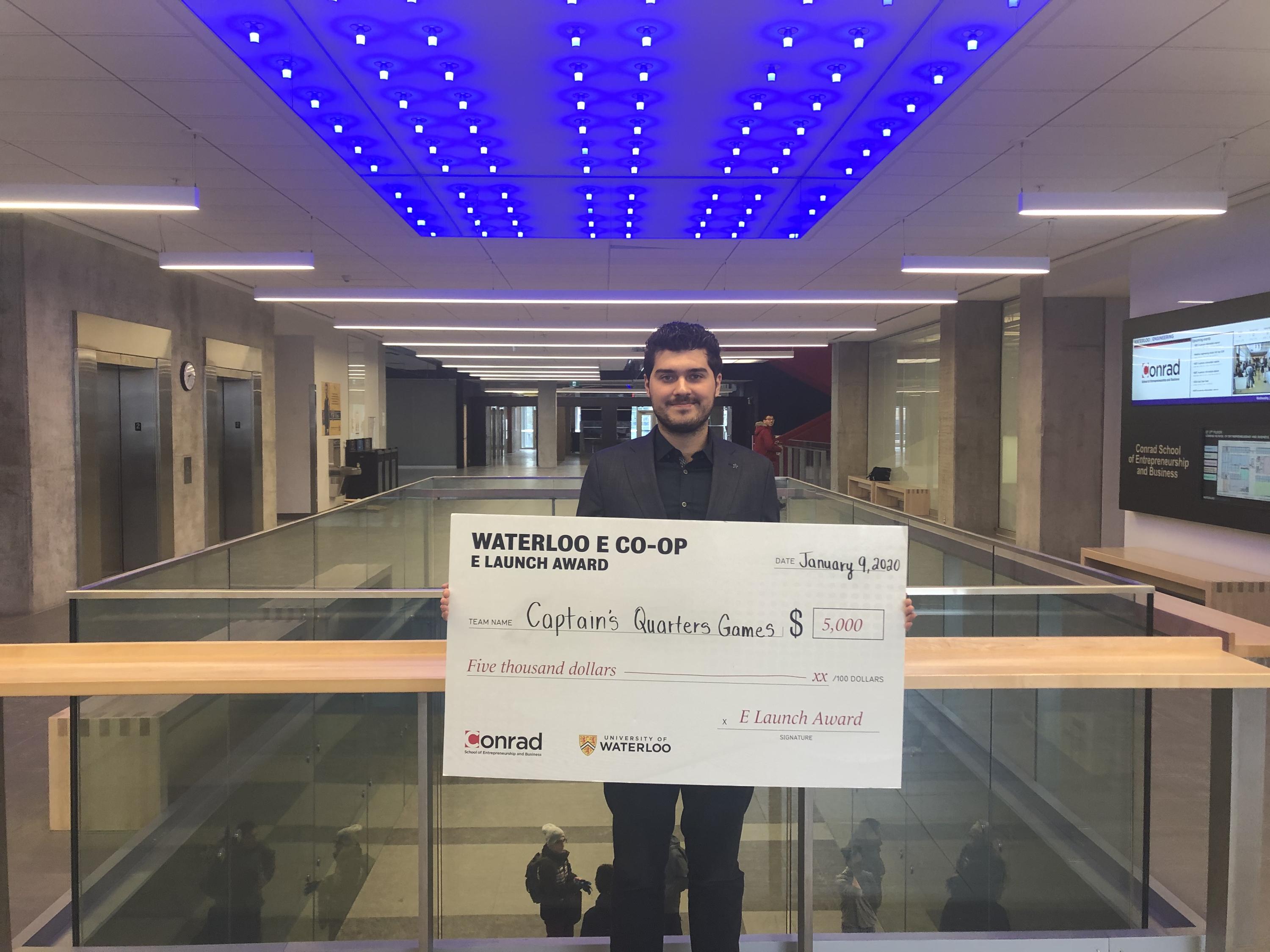 Arman Naziri, founder of Captain's Quarters Games holding cheque for $5,000