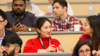 Students gather in lecture hall in coversation