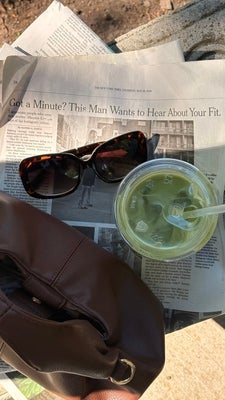 Hearty Matcha_green match on top of newspaper next to sunglasses and brown purse.