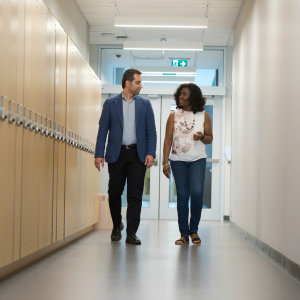 two students walking down hallway next to lockers