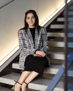 Rashi Jaising in black and white blazer sitting on stairs