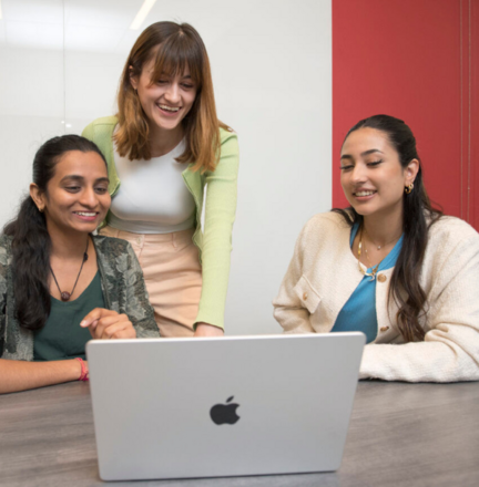 students gather around laptop to work
